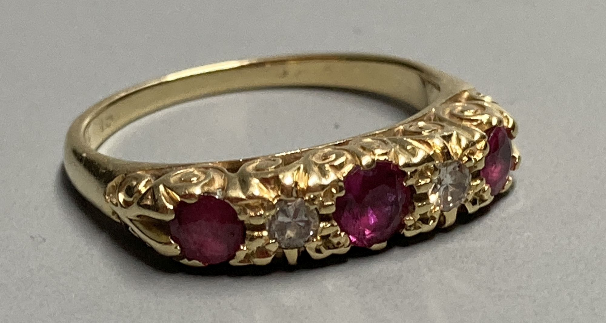 An 18ct Victorian style two stone diamond and three stone ruby set half hoop ring, size K/L. gross 3.1 grams.